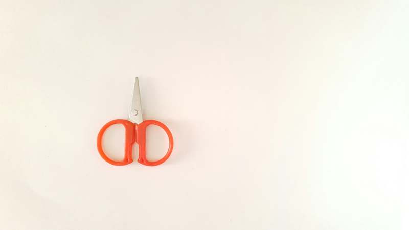 Close-up of precision stainless steel eyebrow scissors on a marble surface with soft lighting